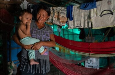 Indigenous woman carrying a toddler on her arms