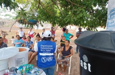 personal de OPS entregando filtros y tanques  de agua a comunidad