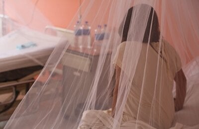 Chica sentada en una cama, de espaldas