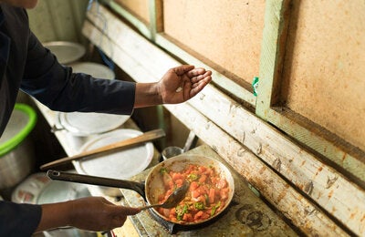 A person is adding salt to food as it cooks