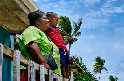 A woman and a boy looking out from a wood house