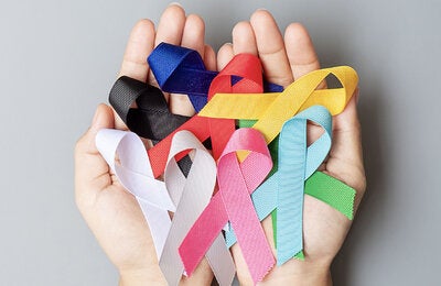 Hands with ribbon of the different colors representing various cancer types