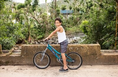 Niño de unos 11 años sentado sobre una bicicleta mirando a la cámara
