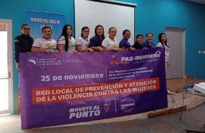 Grupo de mujeres participantes sosteniendo una pancarta