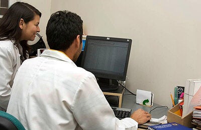 Two health workers looking at a computer monitor.