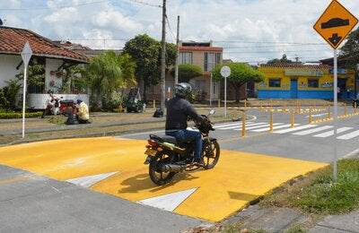 Motociclista en la calle pasando un reductor de velocidad
