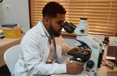 Man in lab looking through the microscope