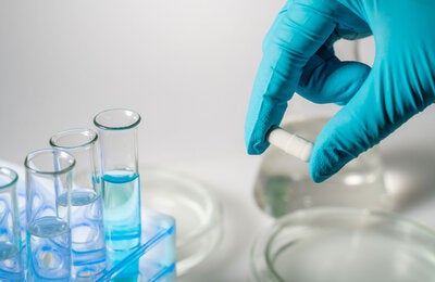 Mano con guante trabajando en un laboratorio.