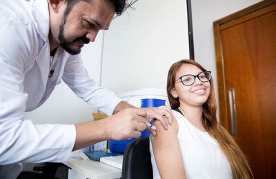 Profissional de saúde aplicando vacina em menina adolescente