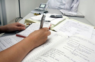Una persona escribiendo observaciones en un cuaderno.