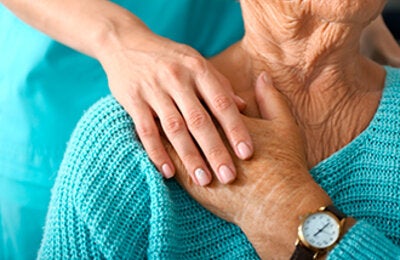 Older patient holding hands with carer