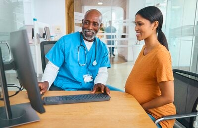 Male doctor and pregnant patient review electronic medical records