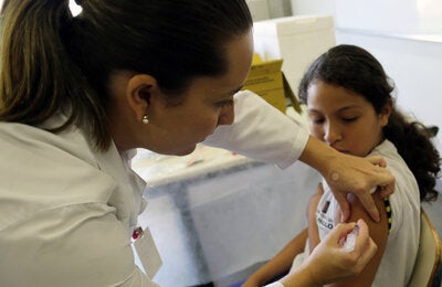 vacunando un niña con uniformer escolar