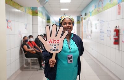personal de salud sostiene una pancarta alusiva a la higiene de manos