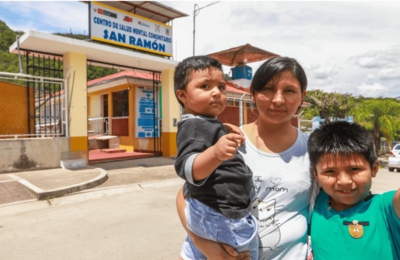 madre junto a sus niños en las afueras de un centro de salud mental comunitario