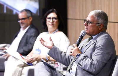 Dr. Cristian Morales, de cabelos brancos, discursa com microfone na mão