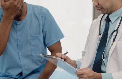 Doctor talking with patient in hospital, male patient lying in bed and doctor providing care, giving advice and encouragement iStock Credit Ashi Sae Yang