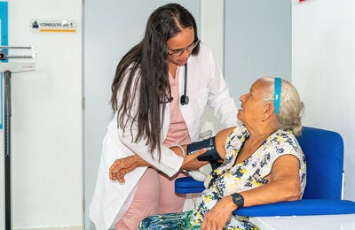 Atenção Primária - Uma mulher idosa tem sua pressão arterial verificada