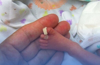 Foot of premature baby on a mother's hand