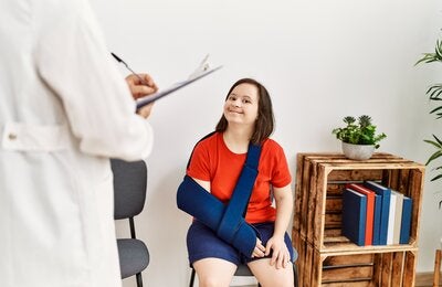 Brunette woman with Down syndrome sitting with her arm in a sling in the waiting room