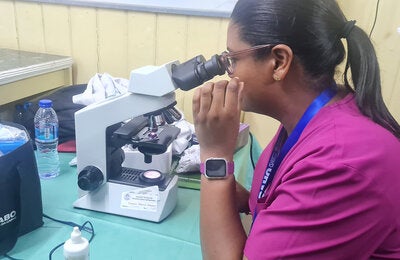 woman looking through microscope