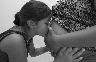 Menina beija a barriga de gestante