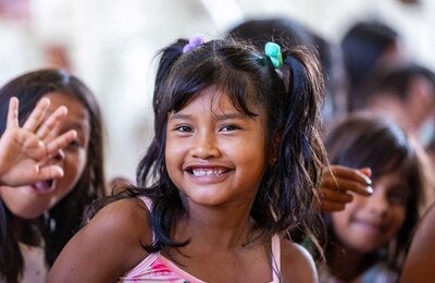 Menina sorrindo e acenando para a câmera