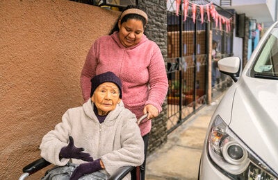 elderly woman in wheelchair being pushed
