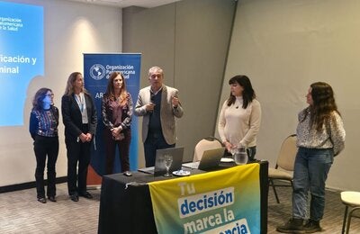 Autoridades dan inicio a la jornada. En la mesa de disertantes, una bandera dice "Tu decisión marca la diferencia"