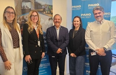 Delegación de salud de São Paulo y equipo de la OPS/OMS posan en el Centro de Operaciones de Emergencia, junto a un banner sobre respuesta a emergencias sanitarias.