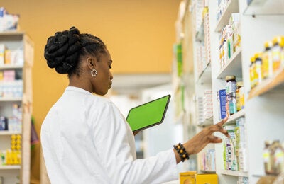 Female pharmacist checking the medicine on shelfs in drugstore