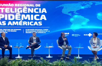 Panelistas sentados con fondo alusivo al evento, mostrando mapa mundi y título del evento