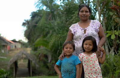 A mother in the Amazon with her smiling daughter and son