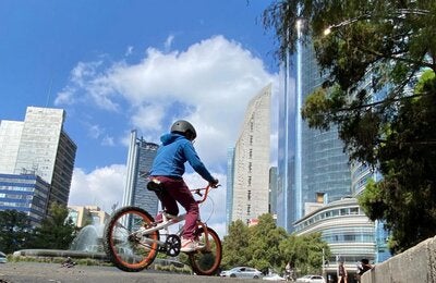 Niño en bicicleta en Ciudad de México con un cielo azul