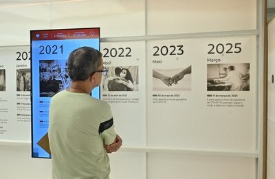 A visitor views an interactive timeline installation at the exhibition “The Infinite Memory of the Pandemic: The History of COVID-19 Through the Experiences of Brazilians,” conceived as a physical extension of the Digital Memorial to connect the public with the stories and experiences preserved on the Portal.
