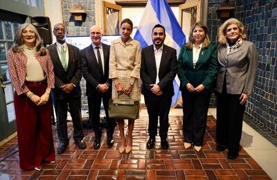 siete personas paradas en frente de la bandera de El Salvador