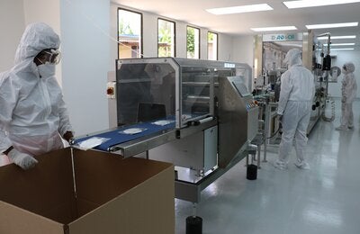 Operarios trabajando en línea de mascarillas instalada en COMBIOMED como parte de proyecto con UE y OPS