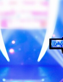 silueta de dos cámaras grabando un escenario con luces