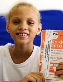Una niña muestra su certificado de vacunación contra el VHP en Brasil
