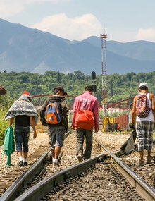 migrants walking on railroad tracks
