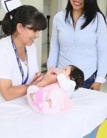 nurse interacts with infant as parent watches
