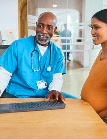 Male doctor and pregnant patient review electronic medical records