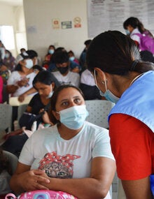 Personal de salud conversa con paciente en una sala de espera 
