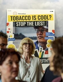 Imagen de un puesto de campaña que advierte sobre las mentiras de los productos del tabaco, con algunas personas a su alrededor.