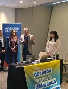 Autoridades dan inicio a la jornada. En la mesa de disertantes, una bandera dice "Tu decisión marca la diferencia"
