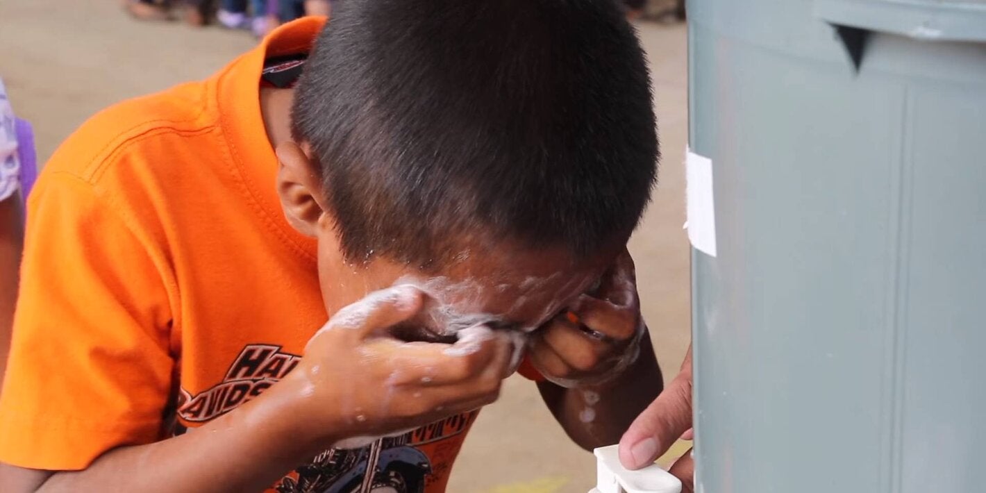 School kid washing his eyes