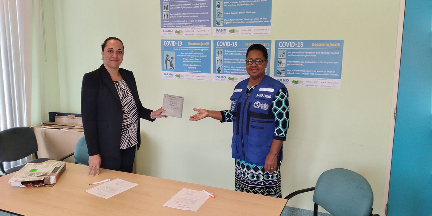 Dr. Karen Lewis-Bell hands over the COVID-19 diagnostic test kits to Dr. Cleopatra Jessurun  Director of the ministry of Public Health.