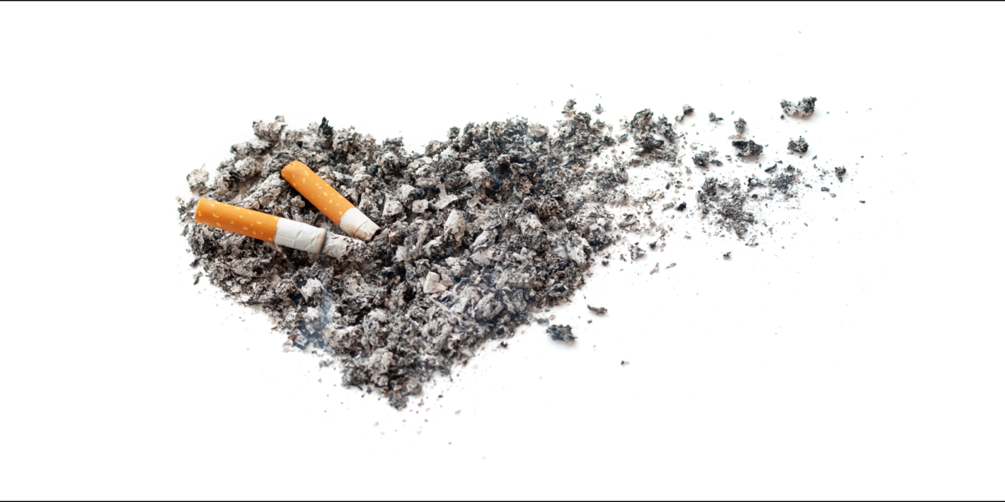 Imagen de una colilla apagándose en un conjunto de ceniza con forma de corazón. A la derecha, parte del corazón de ceniza se deshace