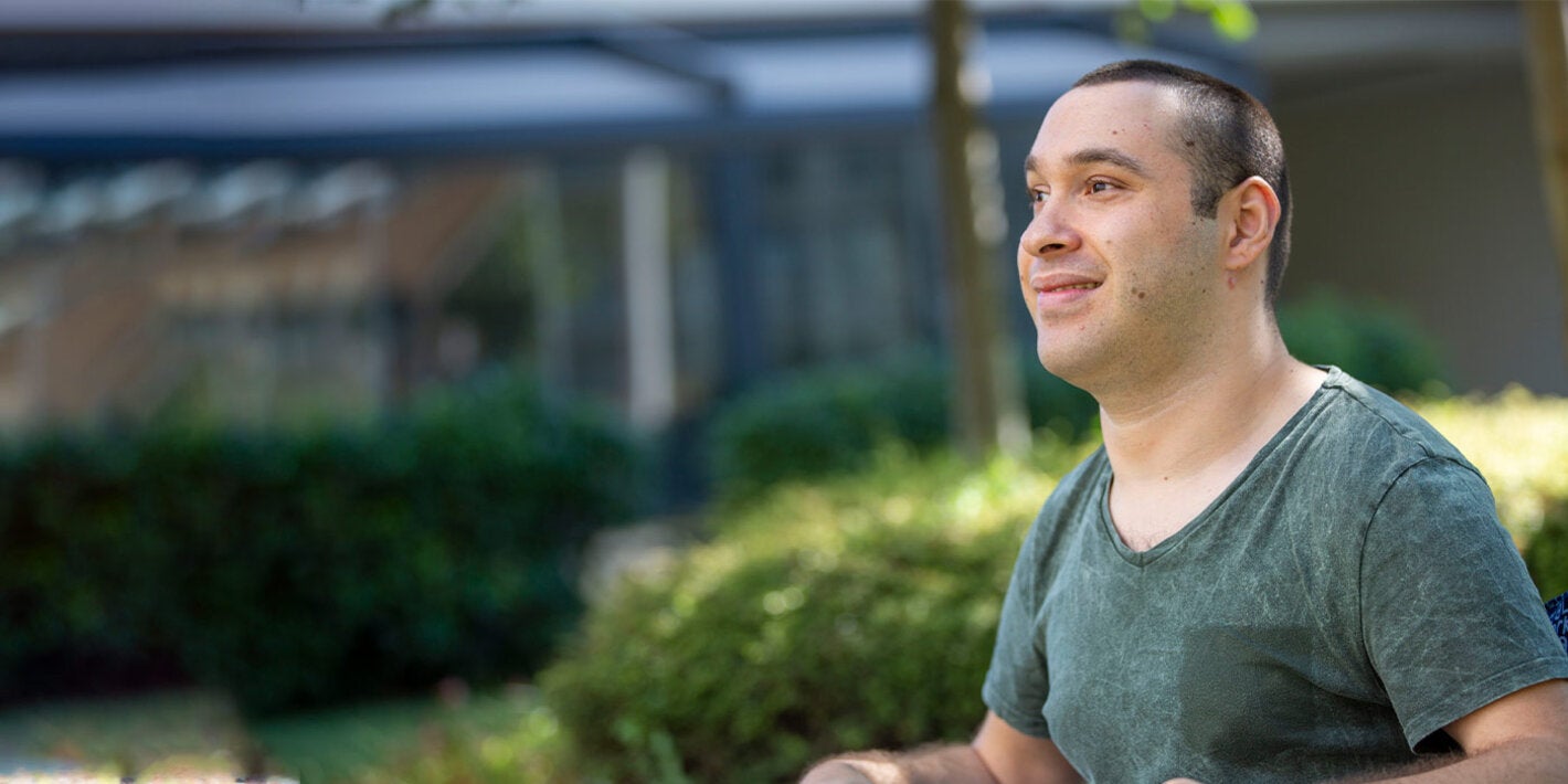 Man with disability sitting on a wheelchair outdoors smiling