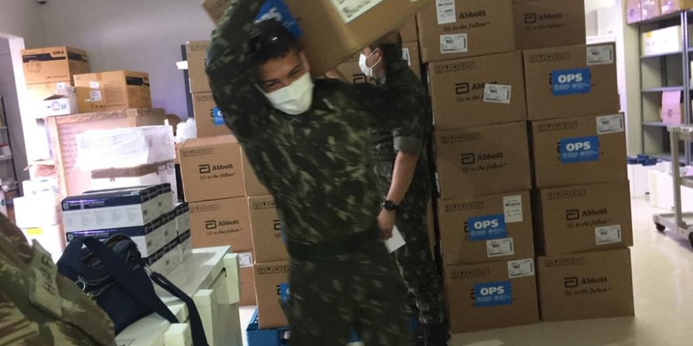 Militares da Força Tarefa da Operação Acolhida, no Brasil, carregam testes para diagnóstico de COVID-19 doados pela OPAS